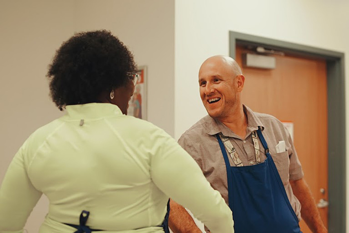 A man in an apron shakes a woman's hand